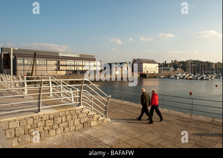 A couple walking at Victoria Dock and the Galeri arts centre Caernarfon Gwynedd north wales summer evening Stock Photo