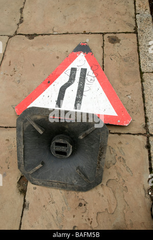 Road Narrows traffic warning sign fallen over on pavement Stock Photo