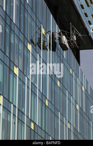 Window cleaners in cradle suspended from one of London's glass towers Stock Photo