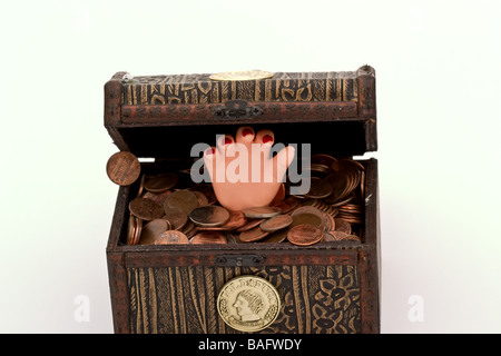 Small plastic hand in a small treasure chest filled with coins Stock Photo