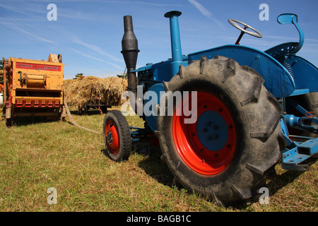 A Lanz Bulldog tractor about to be conected to an old threshing machine Blue sky beyond Limousin France Stock Photo