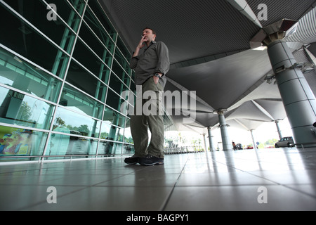 A man smokes a cigarette outside an airport Stock Photo