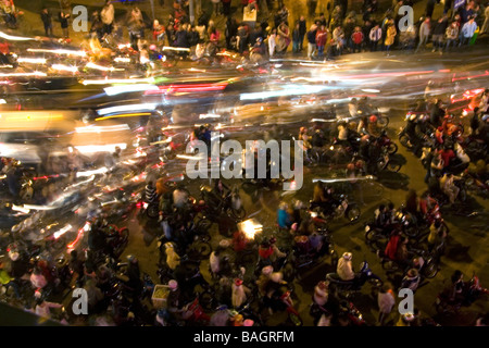 Motion of motorbikes moving through crowds of people celebrating Tet in Hanoi Vietnam Stock Photo