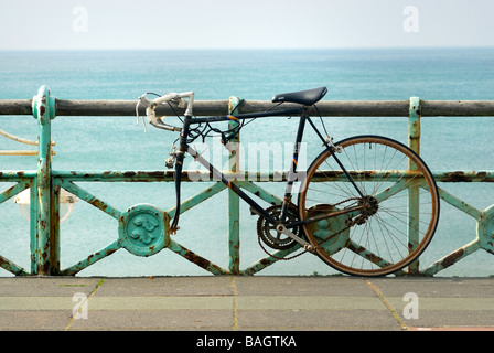 Old bicycle chained to railings on Brighton Seafront Stock Photo