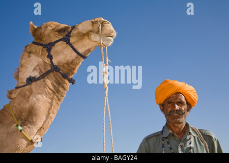 Man standing beside a camel at Osian Camel Camp, Osian, Rajasthan, India Stock Photo