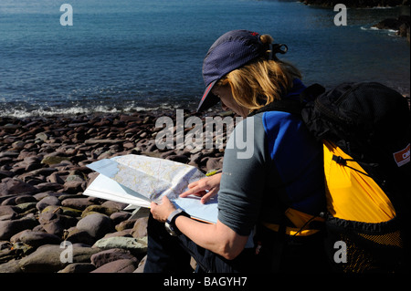 Female walker reading a map and checking the route while on the Pembrokeshire Coastal Path Stock Photo