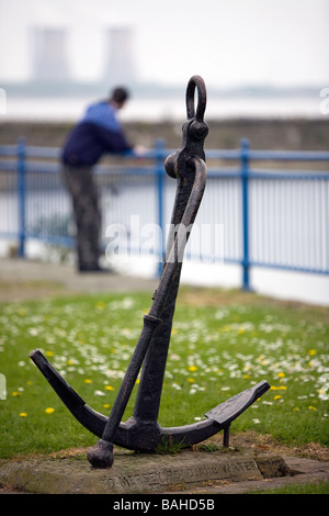 Lonely teenager leans on railings over the River Mersey and contemplates his problems. An anchor stands proud in the foreground Stock Photo