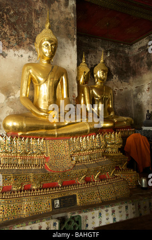 Gold buddha statues line the galleries that encircle the main building containing Buddha at Wat Suthat in Bangkok Thailand Stock Photo