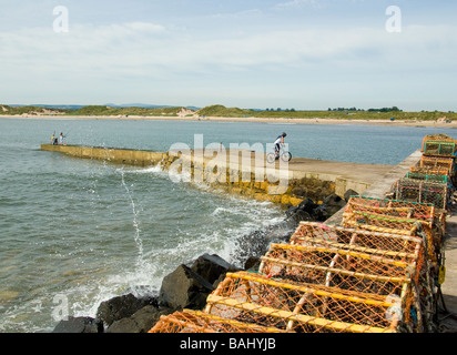 boy jumping on bicycle on harbour wall at Beadnell Bay Northumberland Stock Photo