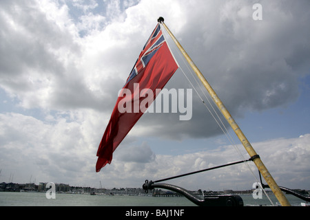 Red ensign flying on the stern of HMS Warrior, showing Portsmouth Harbour in the background