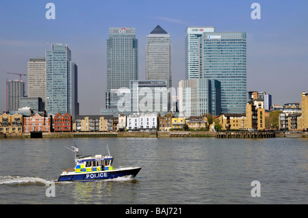 Landmark riverside business & banks offices in Canary Wharf urban development in East London Docklands beside River Thames a Met police patrol boat UK