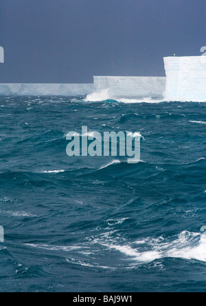 Rough seas batter blue tabular icebergs in the Southern Ocean Antarctica Stock Photo