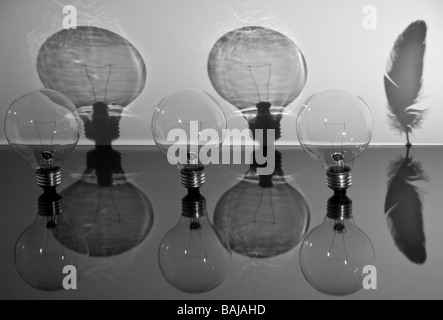 Three light bulbs, one casts a shadow as a feather Stock Photo
