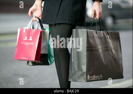 shopping bags from exclusive shops carried by a young woman in Soho London Stock Photo