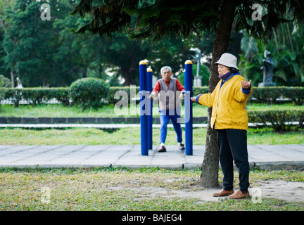two elderly people man and female exercising in a park in the early morning in Taipei dressed in bright cloths Stock Photo