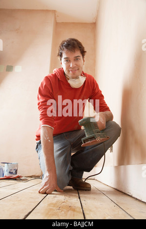 Man holding sanding tool,  in unrenovated room, portrait, Stock Photo