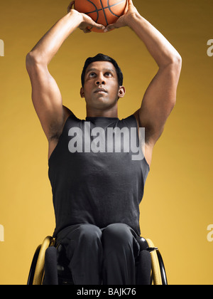 Paraplegic athlete, sitting in wheelchair shooting basketball