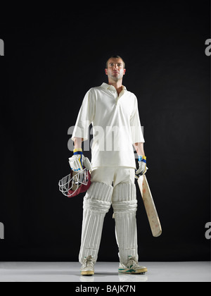 Cricket player, standing holding cricket bat, low angle view Stock Photo