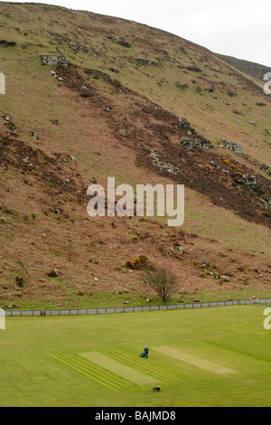 Groundsman preparing cricket pitch situated within rocks and hills in Valley of the Rocks, Lynton, North Devon. Stock Photo