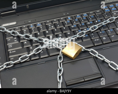 Closeup of laptop keyboard wrapped around with metal chain and locked with padlock Stock Photo