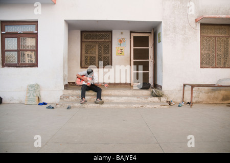 boy plays guitar on doorstep Stock Photo