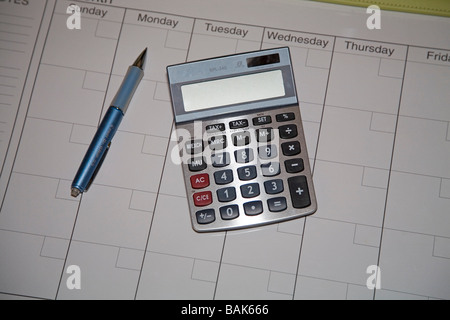 A small cheap hand held calculator and a day planner or date calendar with a ball point pen Stock Photo