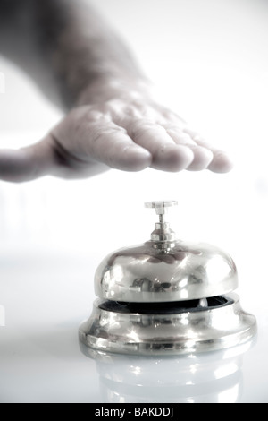 A male person hand about to press a concierge bell for attention on a clear counter top Stock Photo