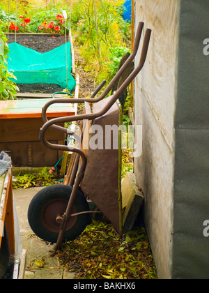 Old Rusty Green Wheelbarrow in British Allotment Stock Photo