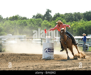 Horse rider participating in flag barrel race event at rodeo Stock Photo