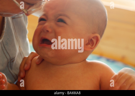 A mother comforts her crying 5 month old baby boy. Baby is half Asian and half Caucasian. Stock Photo