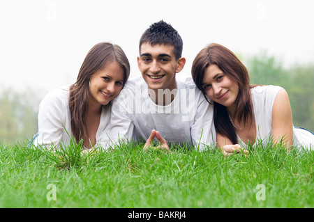 Three young happy friends lying together and smiling Stock Photo