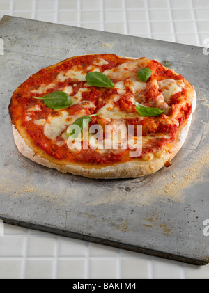 basic pizza garnished with basil leaves Stock Photo