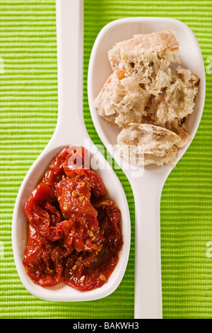 White serving spoons with olive bread pieces and sun dried tomatoes Stock Photo