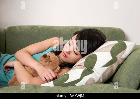 Woman Sleeping On Couch, Holding Teddy Bear Stock Photo