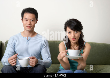 Young People Sitting On Couch, Drinking Tea Stock Photo