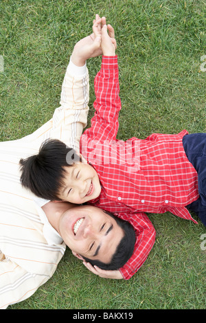 Father And Son Lying Down On Grass Together Stock Photo