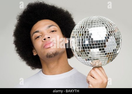 A young man balancing a disco ball Stock Photo