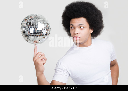 A young man balancing a disco ball Stock Photo