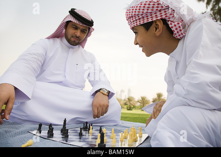 A father and son playing chess in a park