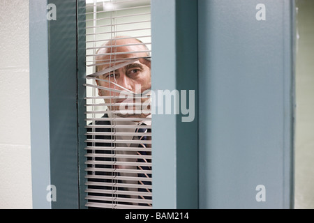 Detective looking through blinds Stock Photo