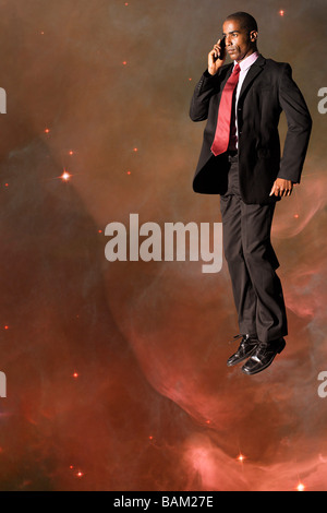 Businessman on cellphone in outer space Stock Photo