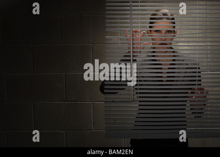 Woman looking through blinds Stock Photo