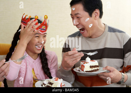 Father And Daughter Eating Birthday Cake With Cake On Their Faces Stock Photo