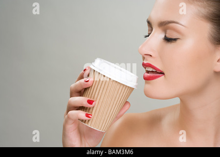 Woman drinking coffee from a paper cup Stock Photo