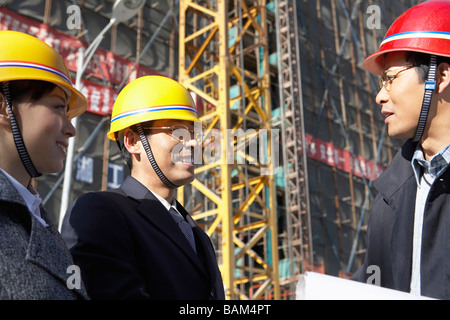 Businesspeople In Construction Site Wearing Hard Hats Stock Photo