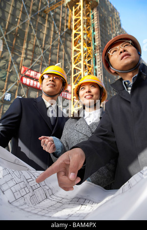 Businesspeople In Construction Site Wearing Hard Hats Stock Photo