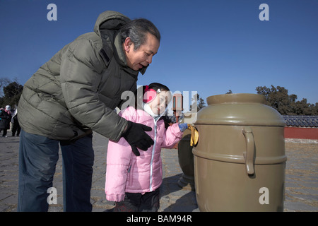 Grandfather Helping His Granddaughter Put A Banana Skin Into A Rubbish Bin Stock Photo