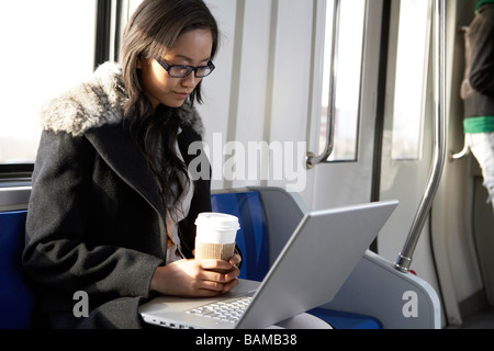 Women Using Her Laptop While Drinking A Takeaway Coffee Stock Photo
