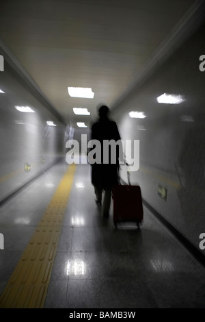 Blurred Image Of A Person Pulling A Suitcase In A Subway Terminal Stock Photo