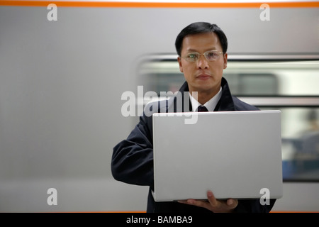 A Man Using His Laptop With A Subway Train In The Background Stock Photo